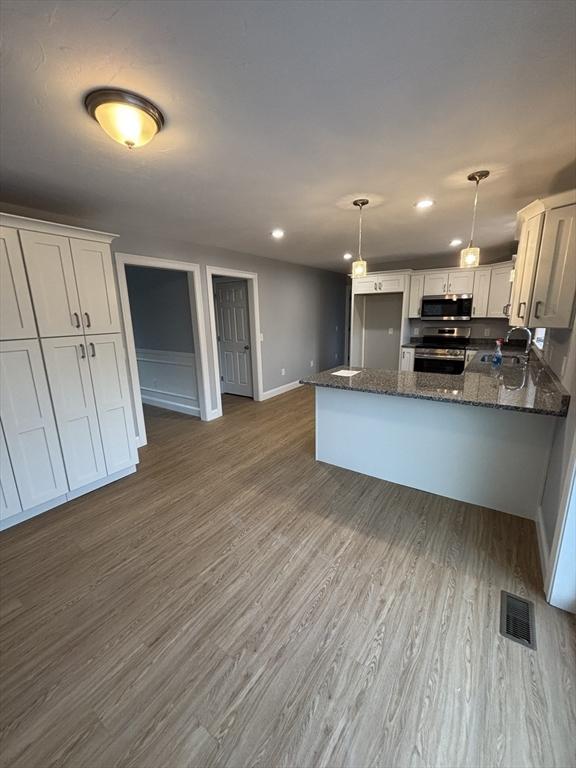kitchen with visible vents, a peninsula, baseboards, white cabinets, and stainless steel appliances