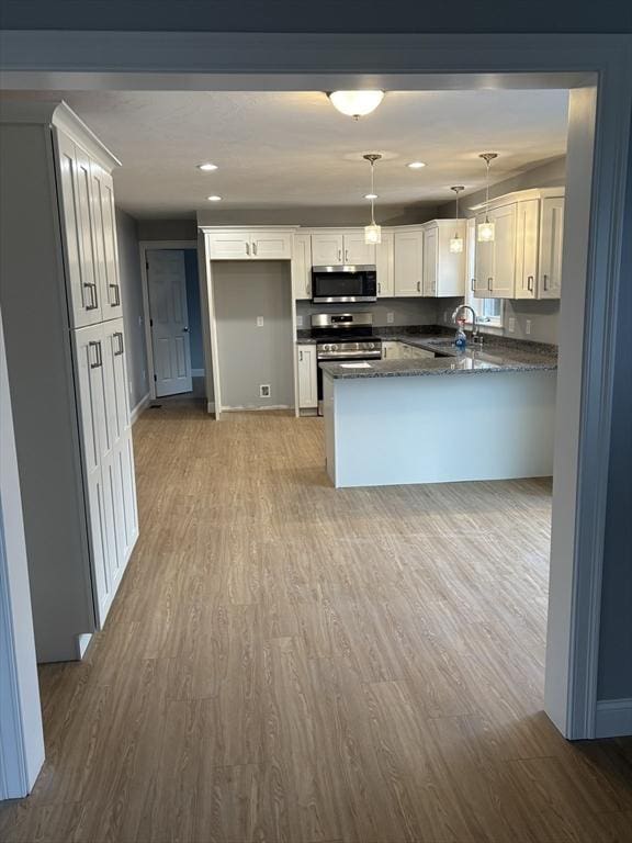 kitchen featuring stainless steel appliances, wood finished floors, and a peninsula