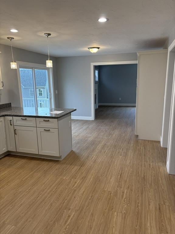kitchen with light wood-type flooring, a peninsula, and decorative light fixtures
