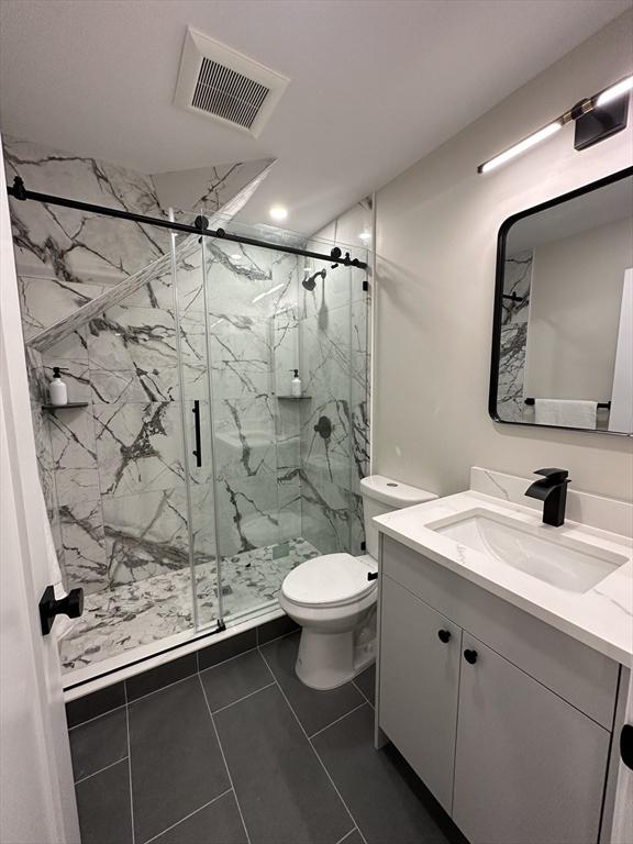 bathroom with tile patterned floors, vanity, toilet, and a shower with door