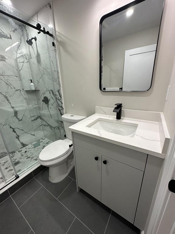 bathroom with tile patterned floors, vanity, toilet, and an enclosed shower