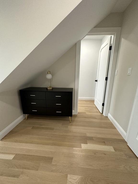 additional living space with light wood-type flooring and vaulted ceiling