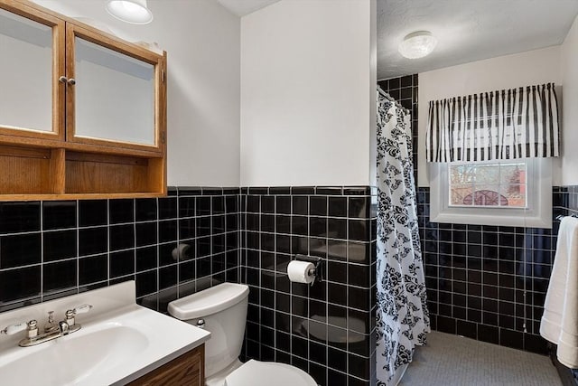 bathroom with a shower with curtain, vanity, tile walls, and toilet