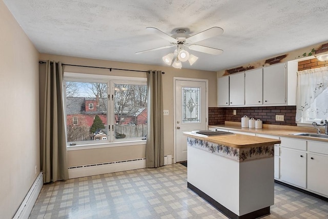 kitchen with a baseboard heating unit, sink, a kitchen island, and white cabinets