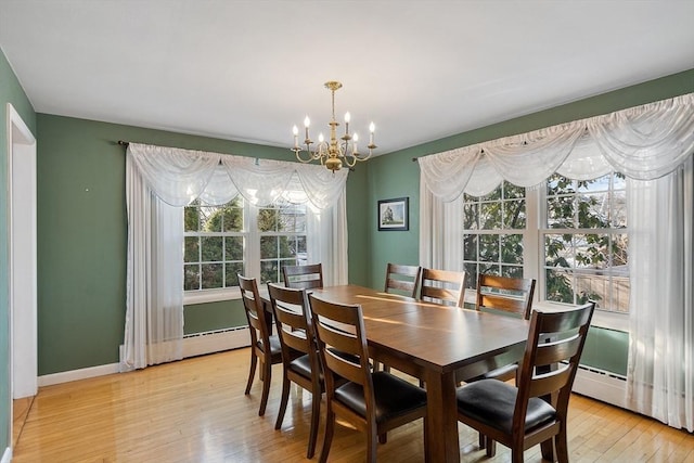 dining space with plenty of natural light, a baseboard heating unit, a notable chandelier, and light hardwood / wood-style floors