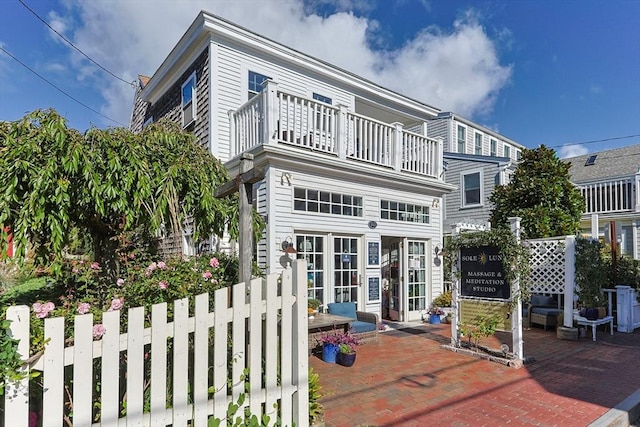 back of house featuring a balcony, a patio area, and french doors