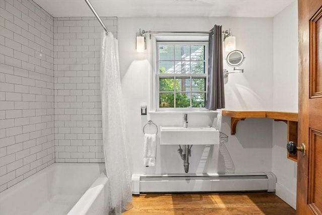 bathroom featuring a baseboard heating unit, wood-type flooring, sink, and shower / bath combo with shower curtain