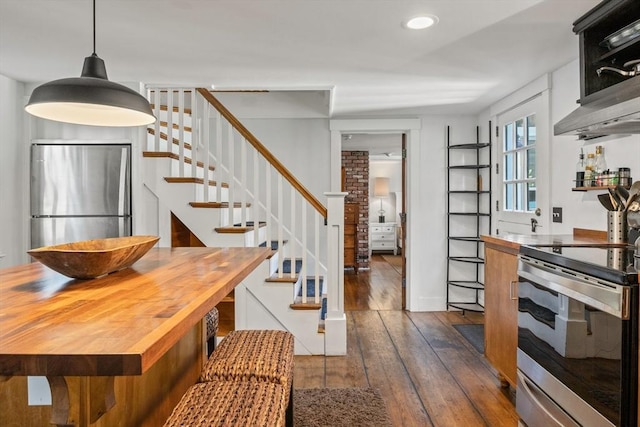 kitchen with dark hardwood / wood-style flooring, decorative light fixtures, wood counters, and appliances with stainless steel finishes