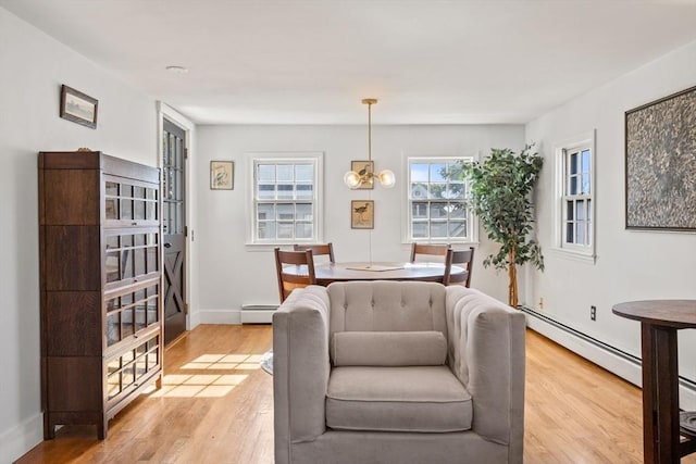 interior space featuring a baseboard heating unit, a chandelier, and light hardwood / wood-style floors