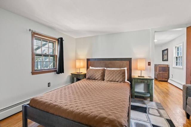 bedroom with a baseboard radiator and light hardwood / wood-style floors