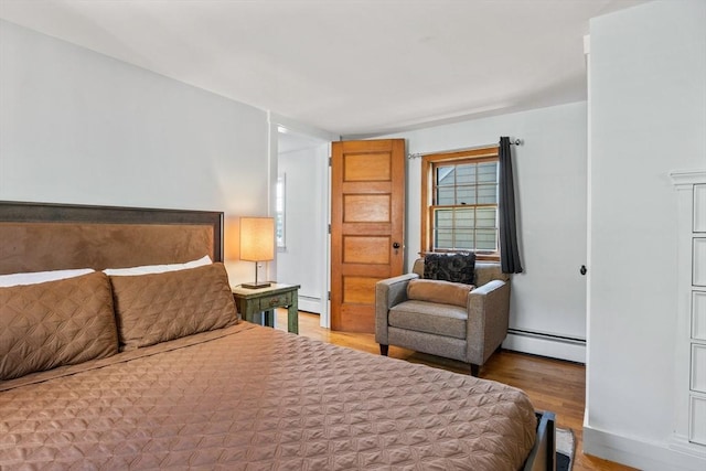 bedroom featuring hardwood / wood-style floors and a baseboard heating unit