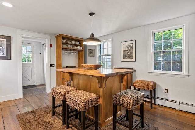 bar featuring hanging light fixtures, dark wood-type flooring, and baseboard heating