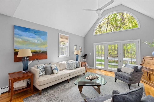 living room with ceiling fan, a wealth of natural light, high vaulted ceiling, and light hardwood / wood-style flooring