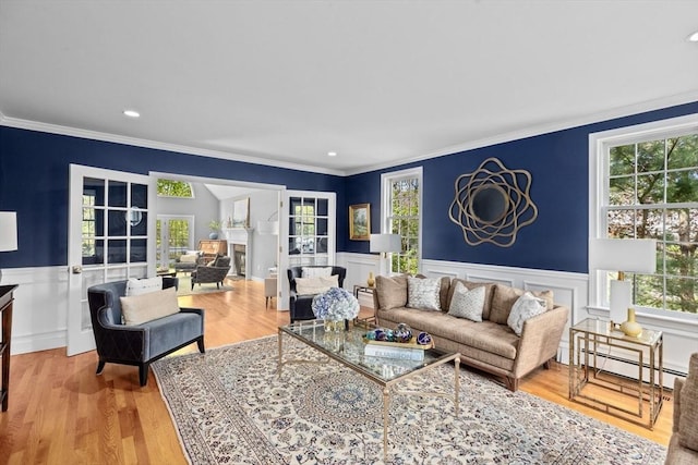 living room with crown molding, a healthy amount of sunlight, light hardwood / wood-style floors, and baseboard heating