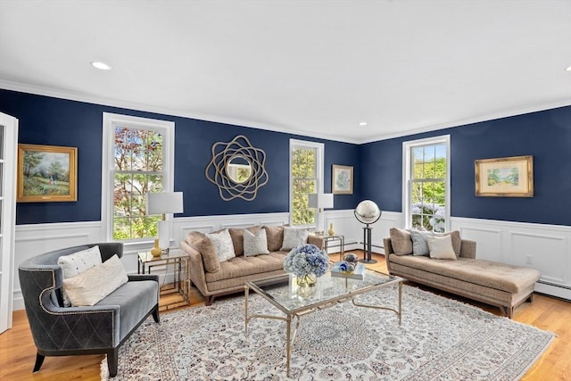 living room with baseboard heating, ornamental molding, and light wood-type flooring