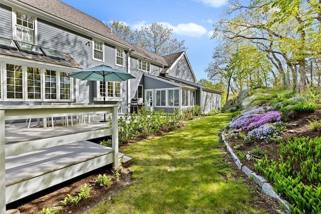 rear view of house featuring a wooden deck and a yard