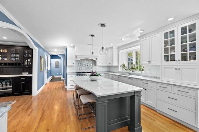 kitchen with custom exhaust hood, white cabinetry, a kitchen island, and decorative light fixtures