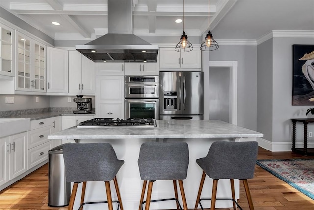 kitchen featuring a breakfast bar, island exhaust hood, light wood finished floors, stainless steel appliances, and white cabinetry