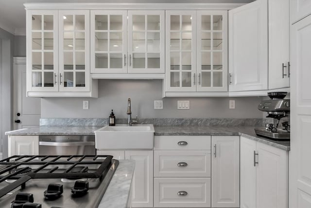 kitchen featuring dishwasher, glass insert cabinets, a sink, and white cabinetry