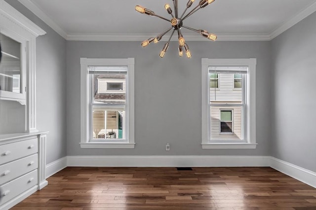 spare room featuring a chandelier, a wealth of natural light, and dark wood finished floors