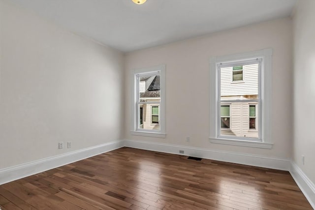 unfurnished room with plenty of natural light, wood-type flooring, and baseboards