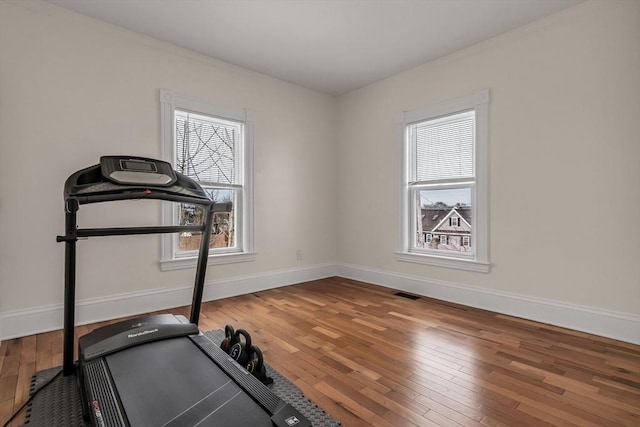 exercise room featuring baseboards, visible vents, and hardwood / wood-style floors