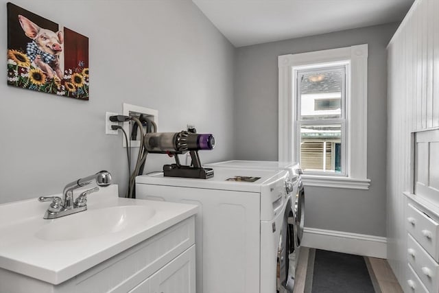 laundry area with washer and clothes dryer, a sink, and baseboards