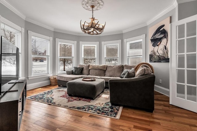 living room featuring a notable chandelier, crown molding, baseboards, and hardwood / wood-style flooring