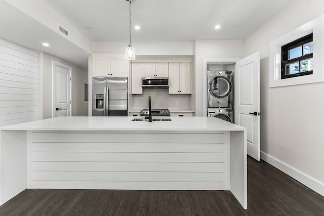 kitchen with stainless steel appliances, stacked washer / drying machine, dark hardwood / wood-style floors, a center island with sink, and white cabinets