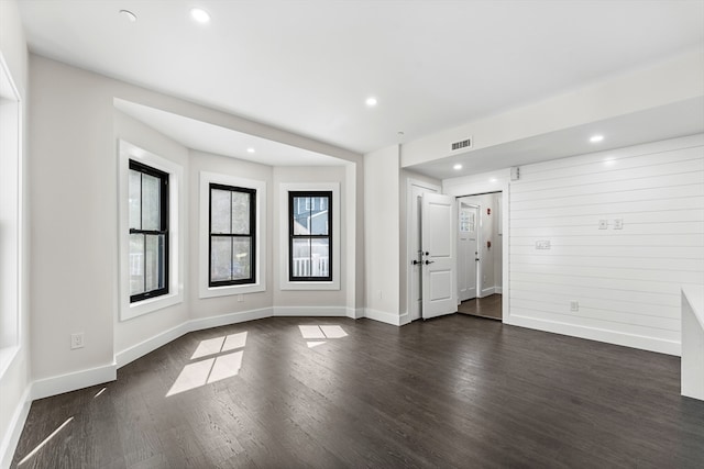 spare room with a wealth of natural light and dark hardwood / wood-style flooring