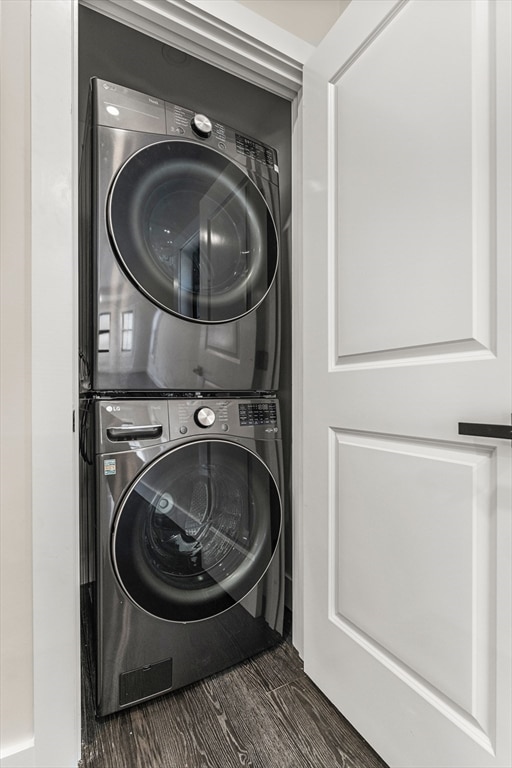 clothes washing area featuring stacked washer / dryer and dark hardwood / wood-style flooring