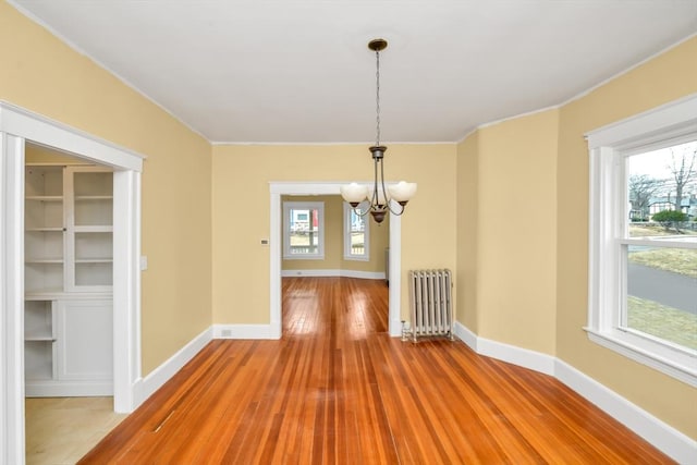 unfurnished dining area with baseboards, a notable chandelier, light wood-style flooring, and radiator heating unit