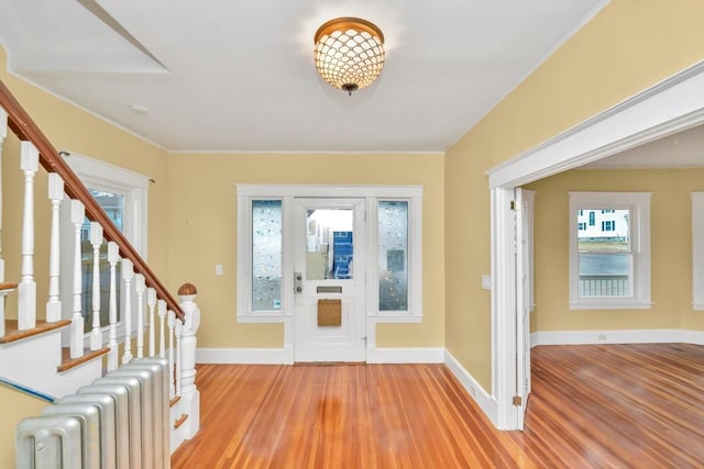 foyer entrance with baseboards, stairway, radiator heating unit, and light wood-style floors