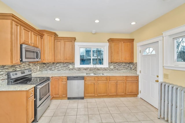 kitchen with light tile patterned floors, radiator, appliances with stainless steel finishes, a sink, and backsplash