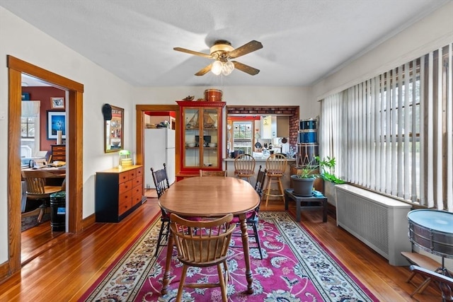 dining room featuring wood finished floors, radiator heating unit, baseboards, and a ceiling fan