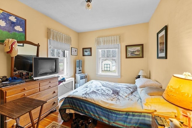 bedroom with radiator heating unit and wood finished floors