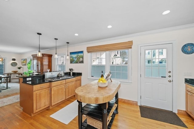 kitchen with hanging light fixtures, ornamental molding, and light hardwood / wood-style floors