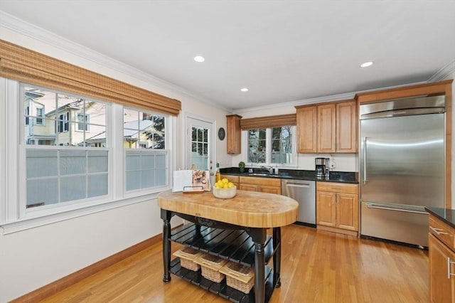 kitchen featuring ornamental molding, appliances with stainless steel finishes, sink, and light hardwood / wood-style flooring