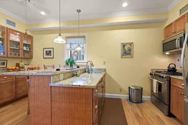 50 Telpgraph St, Boston, MA 02127 - kitchen with appliances with stainless steel finishes, brown cabinetry, light wood-style flooring, ornamental molding, and a peninsula