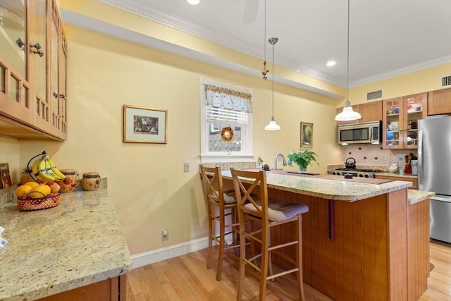 50 Telpgraph St, Boston, MA 02127 - kitchen with appliances with stainless steel finishes, light wood finished floors, a peninsula, crown molding, and brown cabinetry