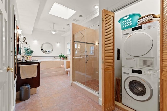 50 Telpgraph St, Boston, MA 02127 - bathroom featuring stacked washing machine and dryer, a skylight, a stall shower, crown molding, and tile patterned flooring