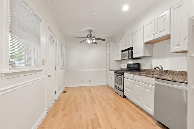 50 Telpgraph St, Boston, MA 02127 - kitchen with appliances with stainless steel finishes, white cabinetry, light wood-type flooring, tasteful backsplash, and crown molding