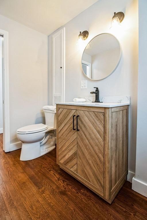 bathroom with toilet, vanity, and hardwood / wood-style floors