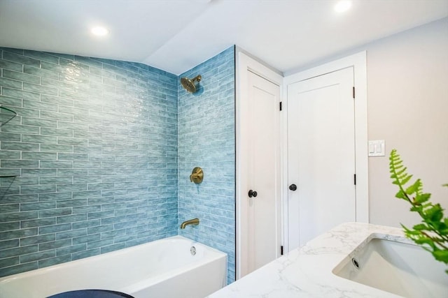 bathroom with tiled shower / bath, vaulted ceiling, and vanity