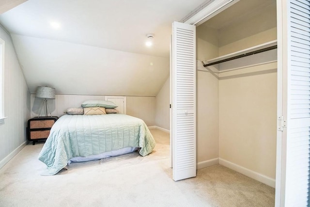 carpeted bedroom with a closet and lofted ceiling