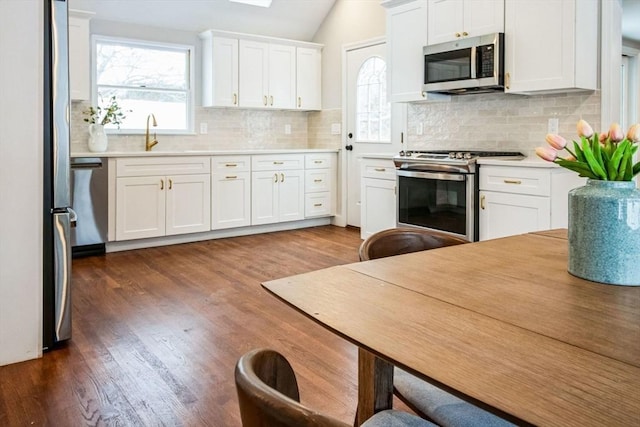 kitchen featuring vaulted ceiling, dark hardwood / wood-style floors, sink, white cabinetry, and stainless steel appliances