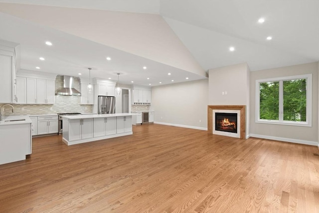 11 Olde Stable Ln, Easton, MA 02356 - unfurnished living room with recessed lighting, a warm lit fireplace, light wood finished floors, and high vaulted ceiling