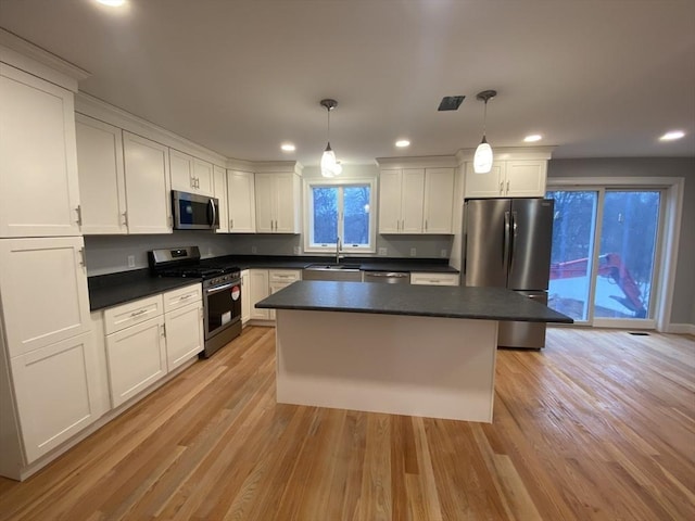 kitchen with pendant lighting, sink, appliances with stainless steel finishes, and light hardwood / wood-style flooring