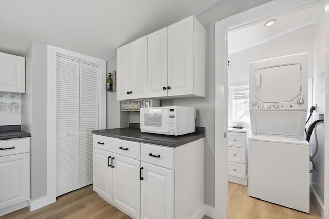 laundry area featuring light wood-style floors, stacked washer and clothes dryer, and laundry area
