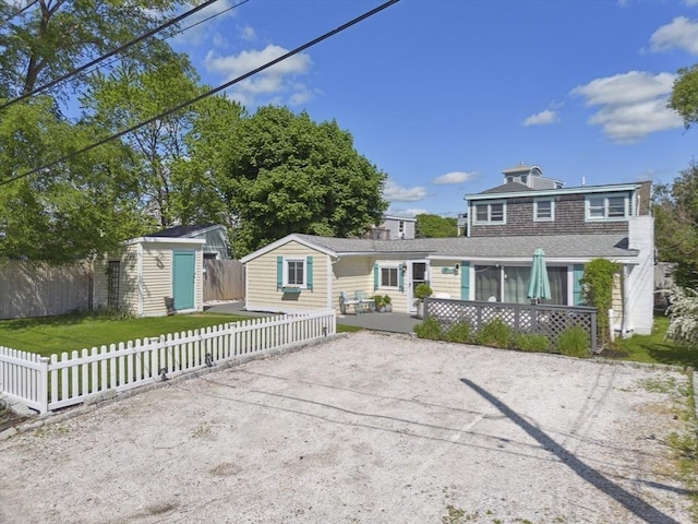 view of front of home with fence private yard, an outbuilding, and a storage unit